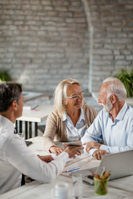 Happy senior woman talking to her husband while having a meeting with manager in the office.